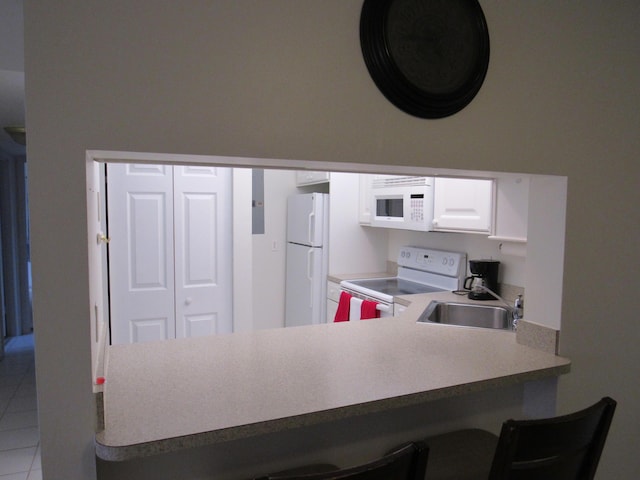 kitchen with white appliances, kitchen peninsula, tile patterned flooring, a breakfast bar area, and sink