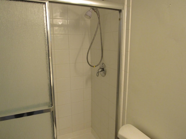 bathroom with toilet and a shower with door