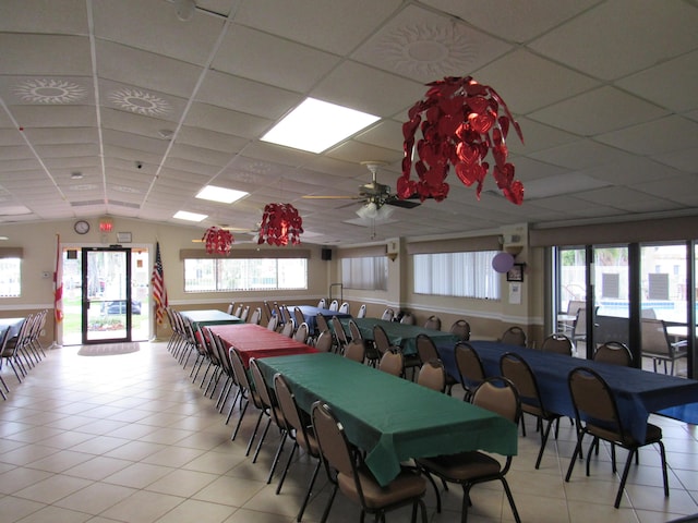 dining area with a paneled ceiling, light tile patterned flooring, and ceiling fan