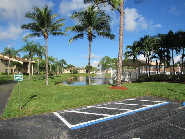 view of parking / parking lot featuring a lawn and a water view