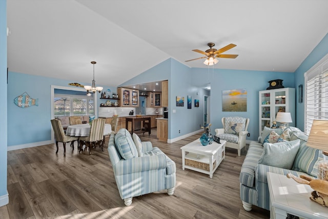 living room with vaulted ceiling, ceiling fan with notable chandelier, and wood-type flooring