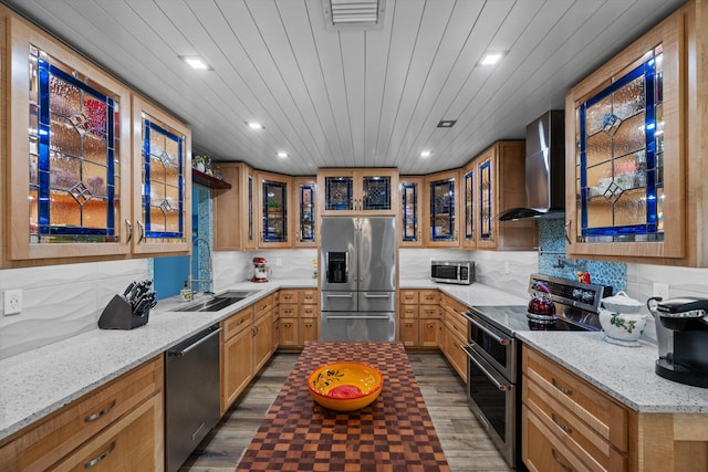 kitchen with light stone counters, sink, stainless steel appliances, and wall chimney exhaust hood