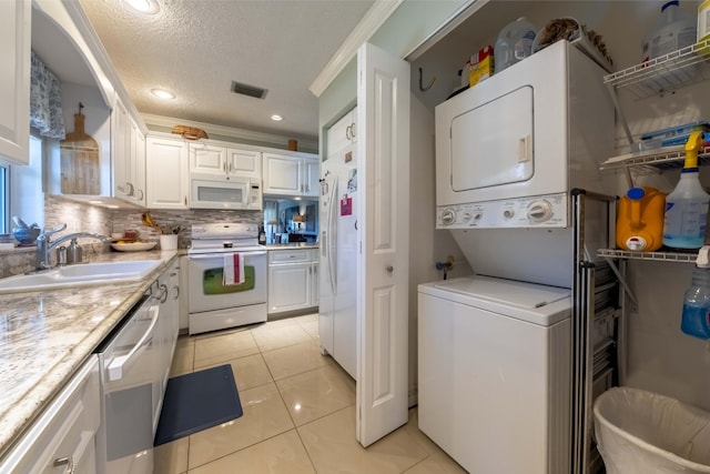 interior space featuring white appliances, white cabinets, stacked washer / drying machine, sink, and light tile patterned floors