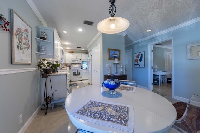 dining space with a textured ceiling, crown molding, and tile patterned flooring