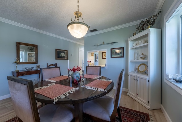 dining room with a textured ceiling, ornamental molding, and light wood-type flooring