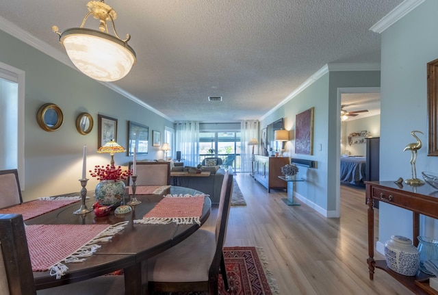 dining area with ceiling fan, wood-type flooring, a textured ceiling, and ornamental molding