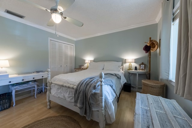 bedroom featuring light wood-type flooring, ceiling fan, a closet, and crown molding