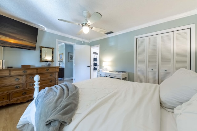 bedroom with a textured ceiling, light hardwood / wood-style floors, a closet, ornamental molding, and ceiling fan