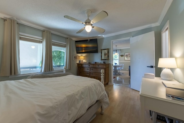 bedroom with a textured ceiling, crown molding, ceiling fan with notable chandelier, and multiple windows