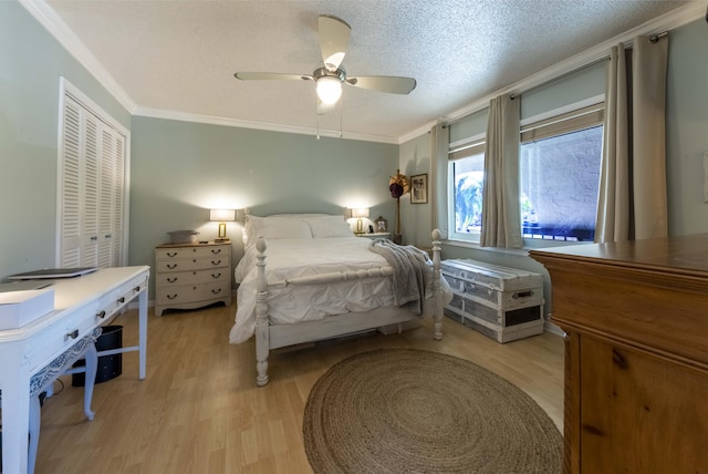 bedroom featuring light wood-type flooring, ceiling fan, a closet, and crown molding