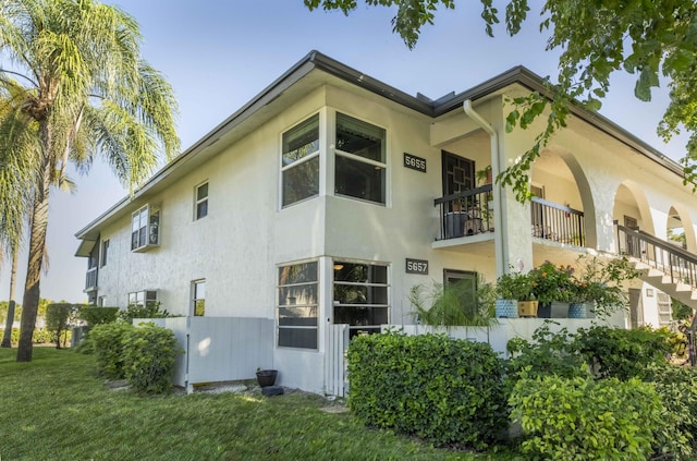 view of property exterior with a lawn and a balcony