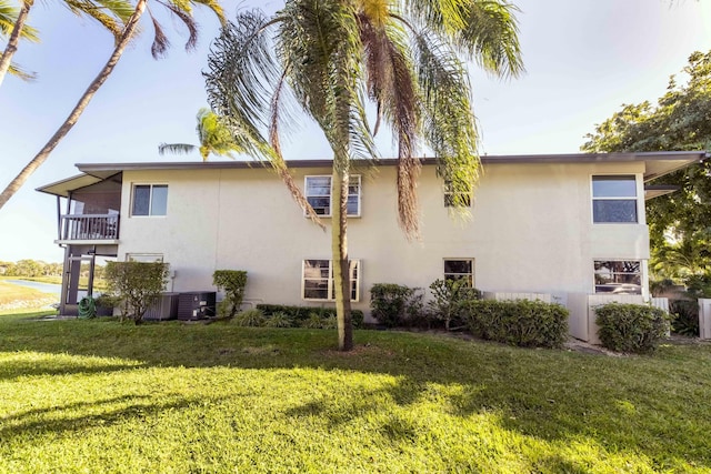 view of side of home with a balcony, a yard, and central air condition unit