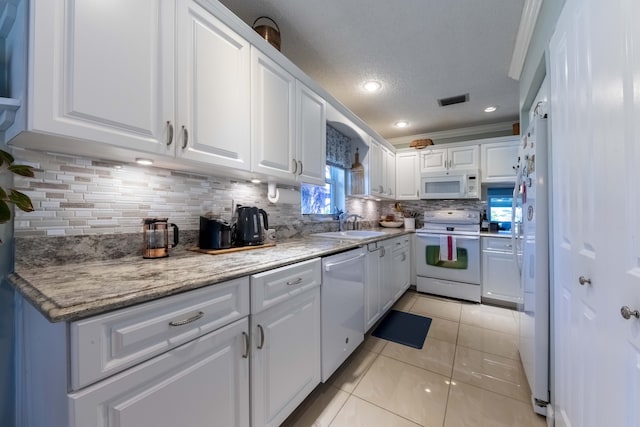 kitchen with light tile patterned floors, decorative backsplash, white cabinets, and white appliances