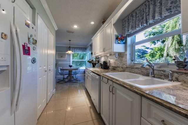 kitchen featuring decorative light fixtures, dishwasher, sink, white refrigerator with ice dispenser, and white cabinets