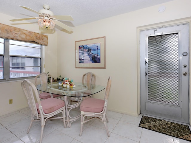 dining area with a textured ceiling, ceiling fan, and light tile patterned floors