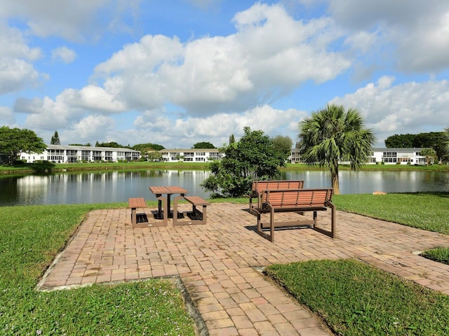 view of home's community featuring a patio area, a lawn, and a water view