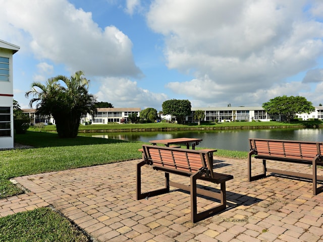 view of property's community with a yard, a patio area, and a water view