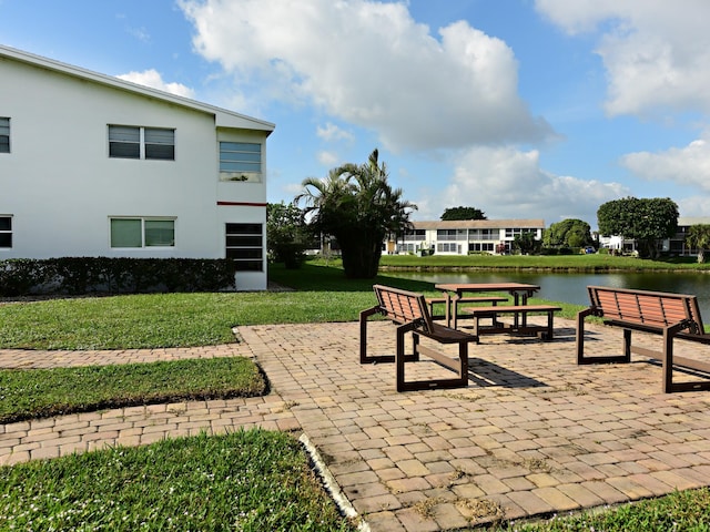 view of home's community with a lawn, a patio, and a water view