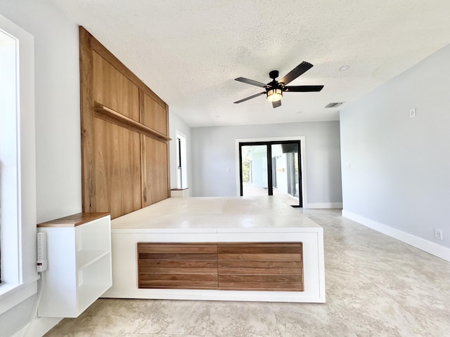 interior space with a textured ceiling and ceiling fan