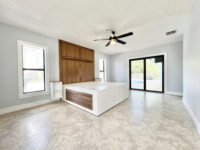 interior space featuring ceiling fan, tile counters, kitchen peninsula, and a textured ceiling