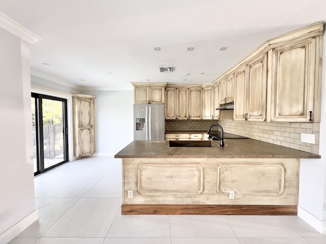 kitchen featuring tasteful backsplash, ornamental molding, stainless steel fridge, and kitchen peninsula