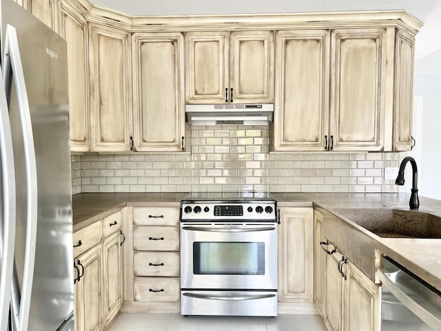 kitchen with stainless steel appliances, sink, light brown cabinetry, and decorative backsplash