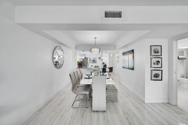 dining space featuring light wood-type flooring and a tray ceiling