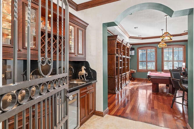 wine room featuring wood-type flooring, indoor wet bar, wine cooler, and crown molding