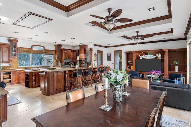 dining area with a raised ceiling, crown molding, and ceiling fan