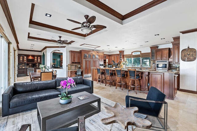 living room with crown molding, a raised ceiling, and ceiling fan