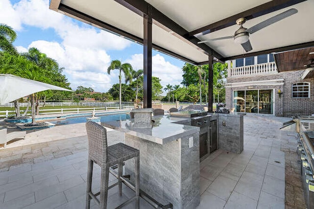 view of patio / terrace with a fenced in pool, area for grilling, an outdoor bar, and ceiling fan