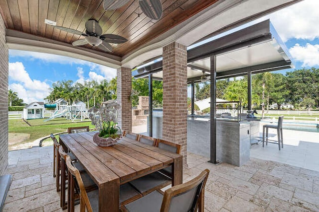 view of patio featuring a playground, ceiling fan, and a bar