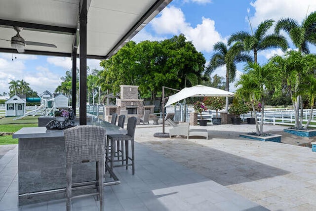 view of patio / terrace with a playground and an outdoor stone fireplace