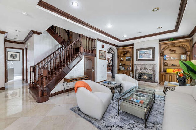 living room featuring ornamental molding, a fireplace, and a raised ceiling