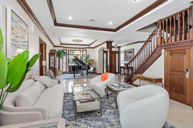 living room with a raised ceiling, crown molding, and ornate columns