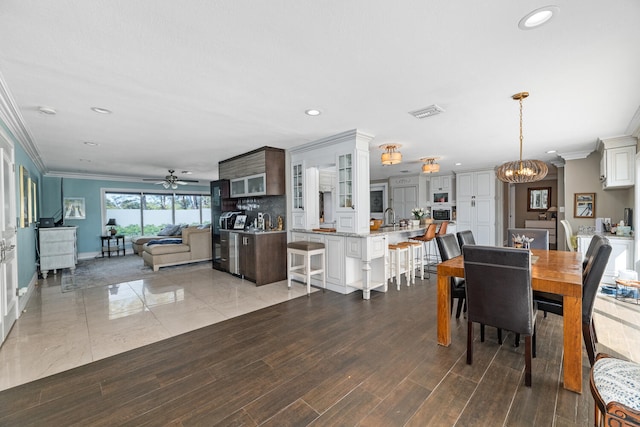 dining space featuring crown molding, sink, ceiling fan with notable chandelier, and light hardwood / wood-style floors