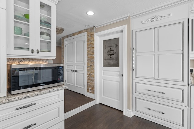 kitchen with light stone countertops, dark hardwood / wood-style floors, and white cabinets