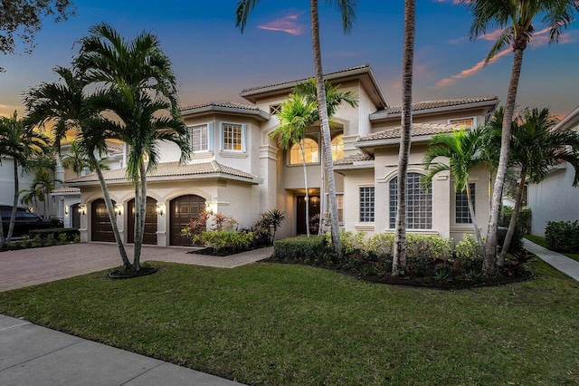 mediterranean / spanish-style house featuring a lawn and a garage