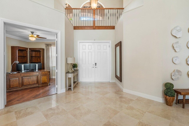 foyer with a high ceiling, ceiling fan, and ornamental molding