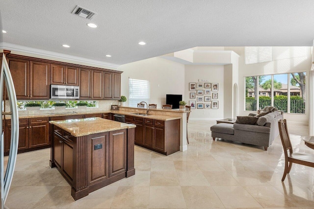 kitchen featuring a kitchen island, stainless steel appliances, dark brown cabinetry, and sink