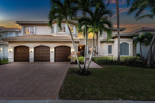 mediterranean / spanish-style home with a garage and a lawn