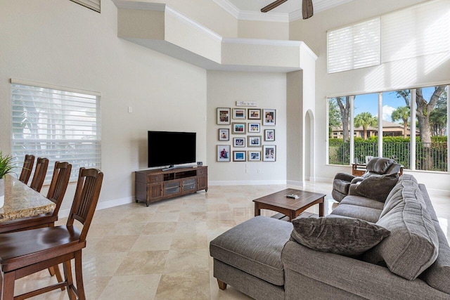 living room featuring a towering ceiling, ceiling fan, and crown molding