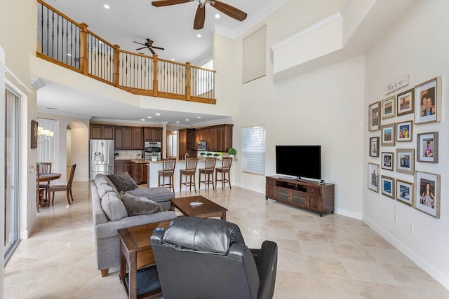 living room featuring a towering ceiling, ceiling fan, and crown molding