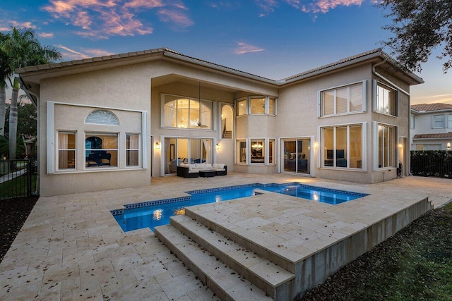 back house at dusk with a patio area, an in ground hot tub, and an outdoor living space