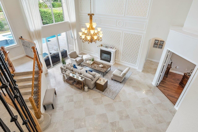 living room featuring a high ceiling, an inviting chandelier, a healthy amount of sunlight, and light hardwood / wood-style flooring