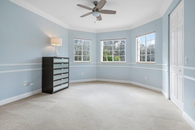 interior space with light colored carpet, ceiling fan, crown molding, and a closet