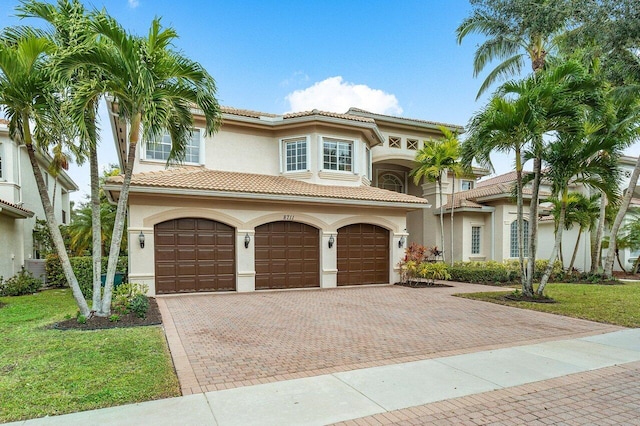 mediterranean / spanish house with central AC unit, a garage, and a front lawn