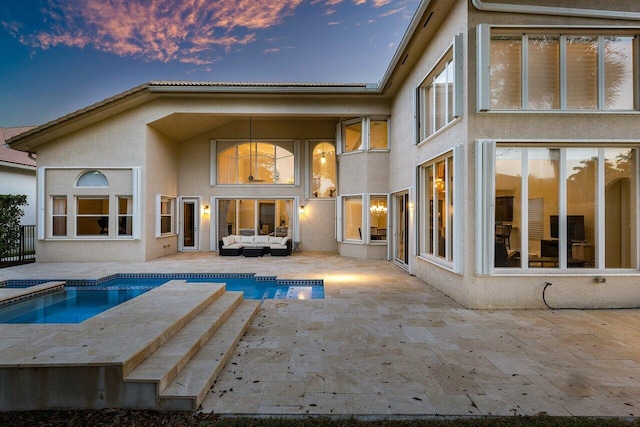 back house at dusk featuring a patio area, a swimming pool with hot tub, and an outdoor living space