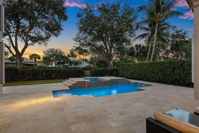 pool at dusk with a patio area, pool water feature, and an in ground hot tub