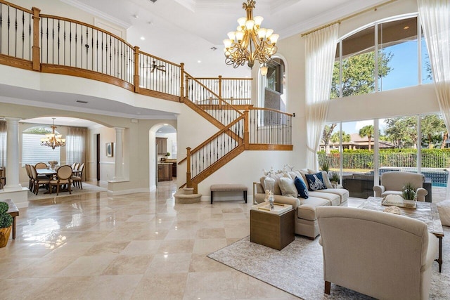 living room with crown molding, a towering ceiling, a chandelier, and decorative columns